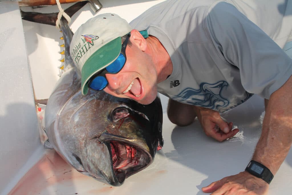 man smiling next to large bigeye tuna