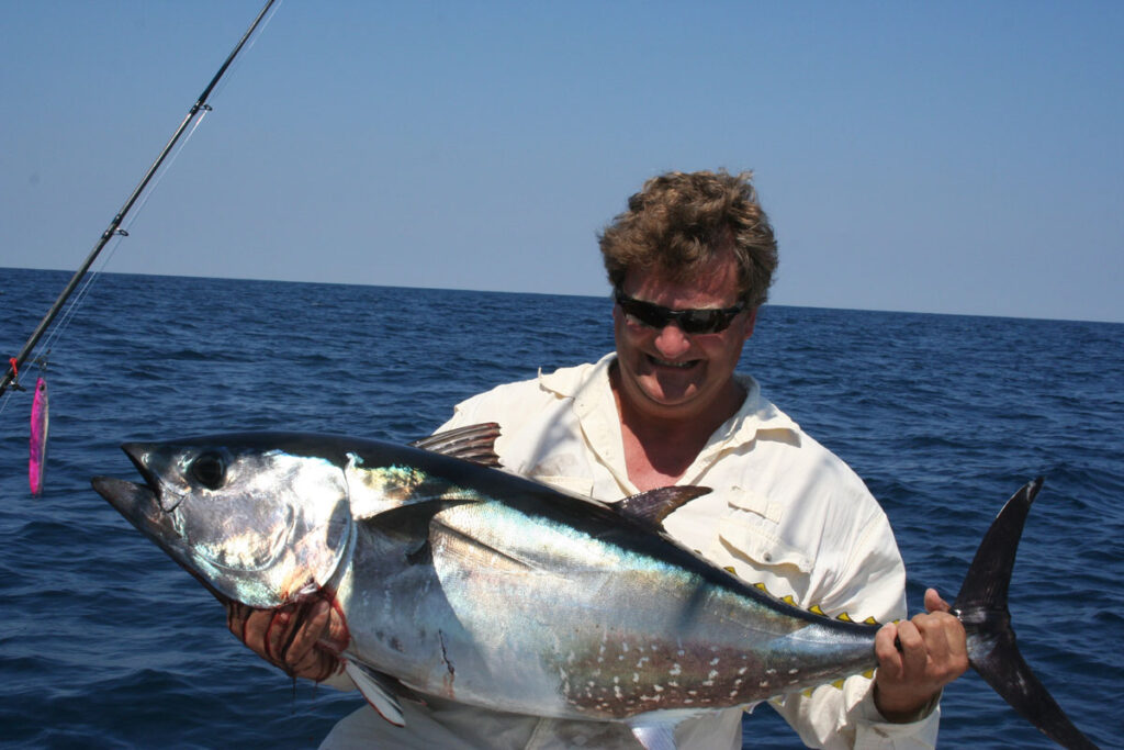 man holding bluefin caught on a pink lure