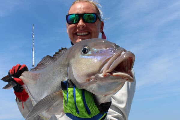 lady angler holds a blueline tilefish close to camera