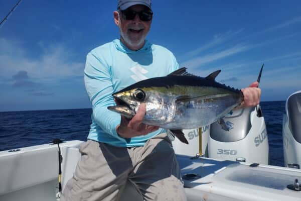 man holds blackfin tuna caught during offshore fishing trip