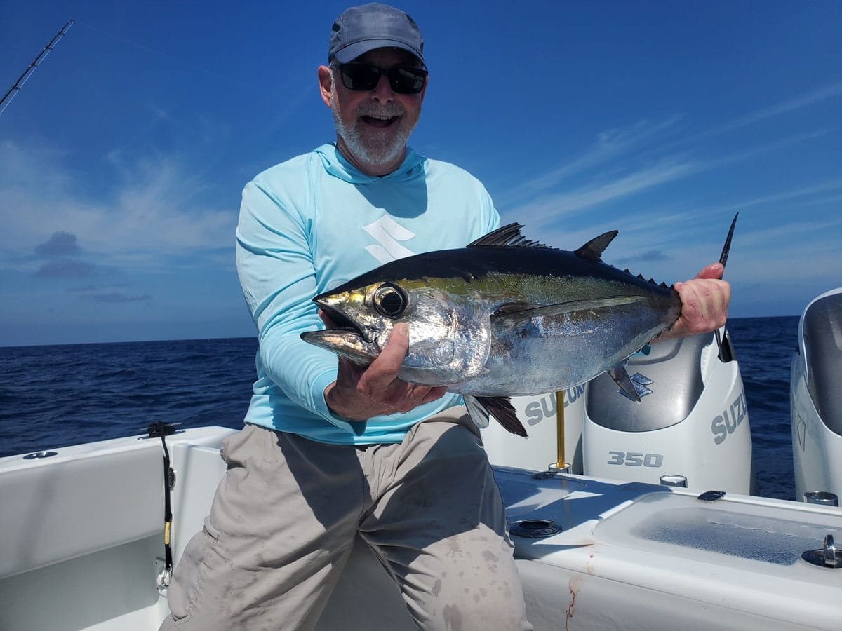 man holds blackfin tuna caught during offshore fishing trip
