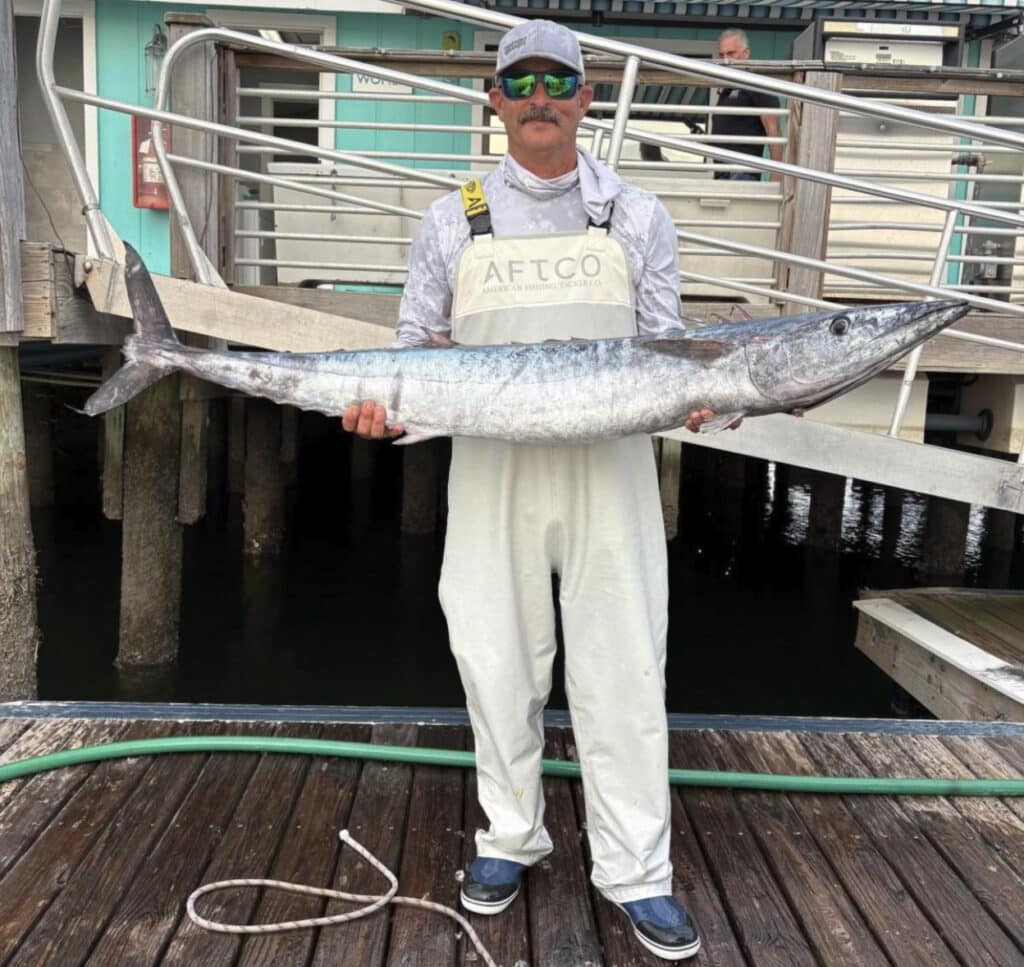 angler holding wahoo back at dock.