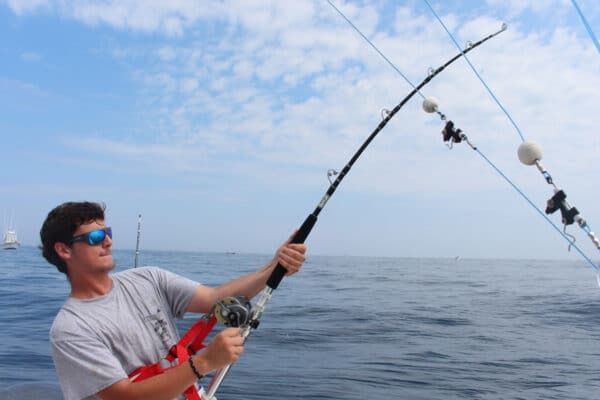 man holding bent rod pulling on a fish